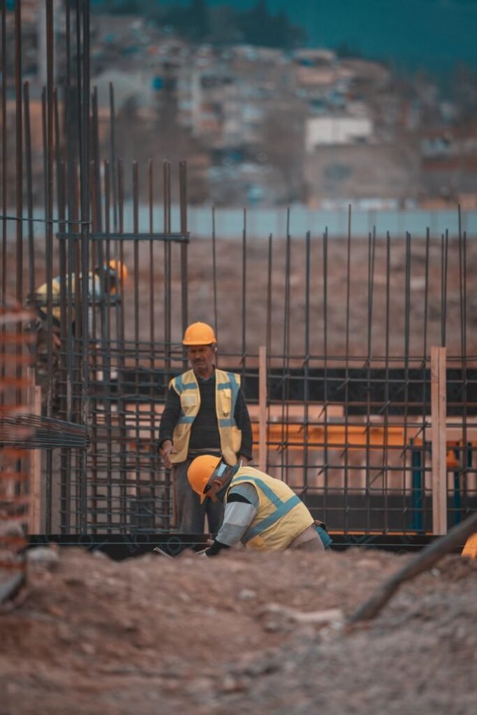Construction workers on site adding steel reinforcement bars. Urban environment, teamwork in progress.